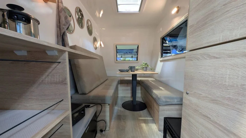 This tiny trailer hides a full camper experience inside – including a lounge and dining area