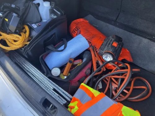 Driver checks car emergency kit, finds flashlights missing, knotted rope, and outdated jumper cables